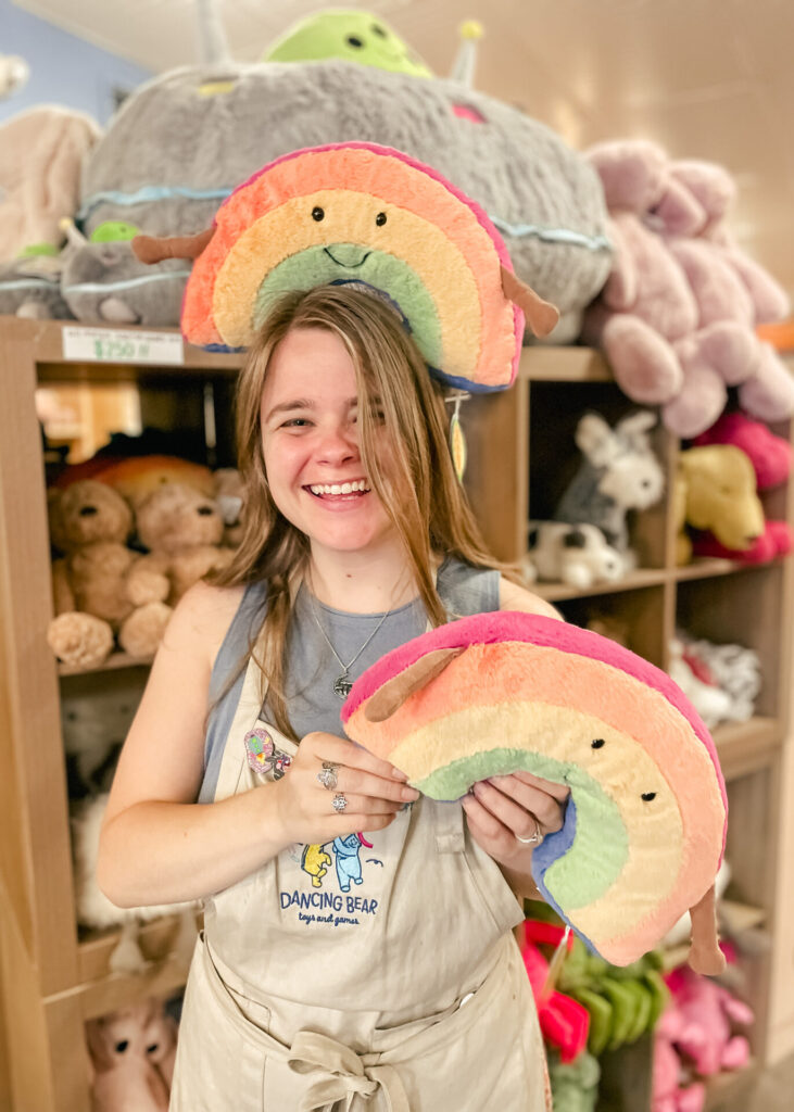 Sacha holding Jellycat rainbow plush toys at Dancing Bear.